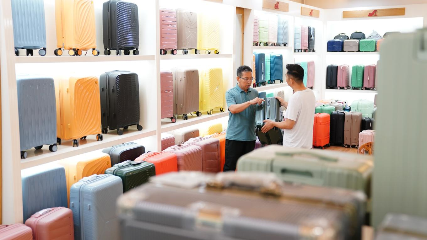 7月4日，白沟新城鹏杰皮具箱包展厅，总经理王金龙向客户介绍箱包产品。孙珞瑜摄